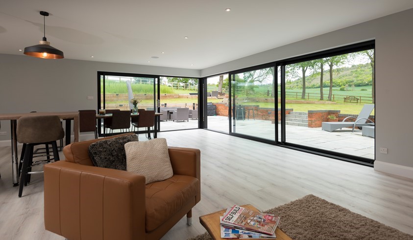 Contemporary aluminium sliding doors opening a living room to the garden in Hungerford