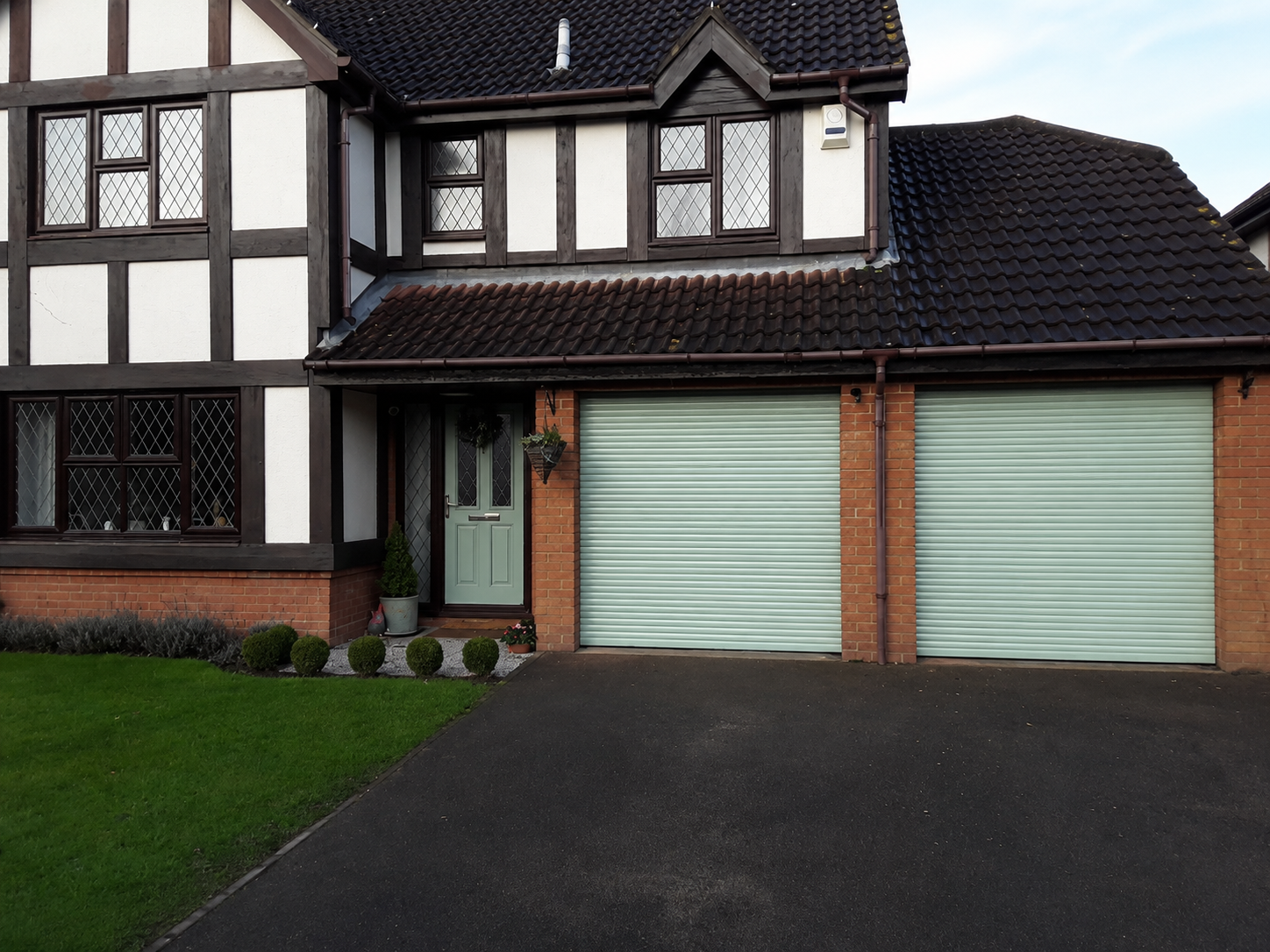Twin white electric roller garage doors on a family home