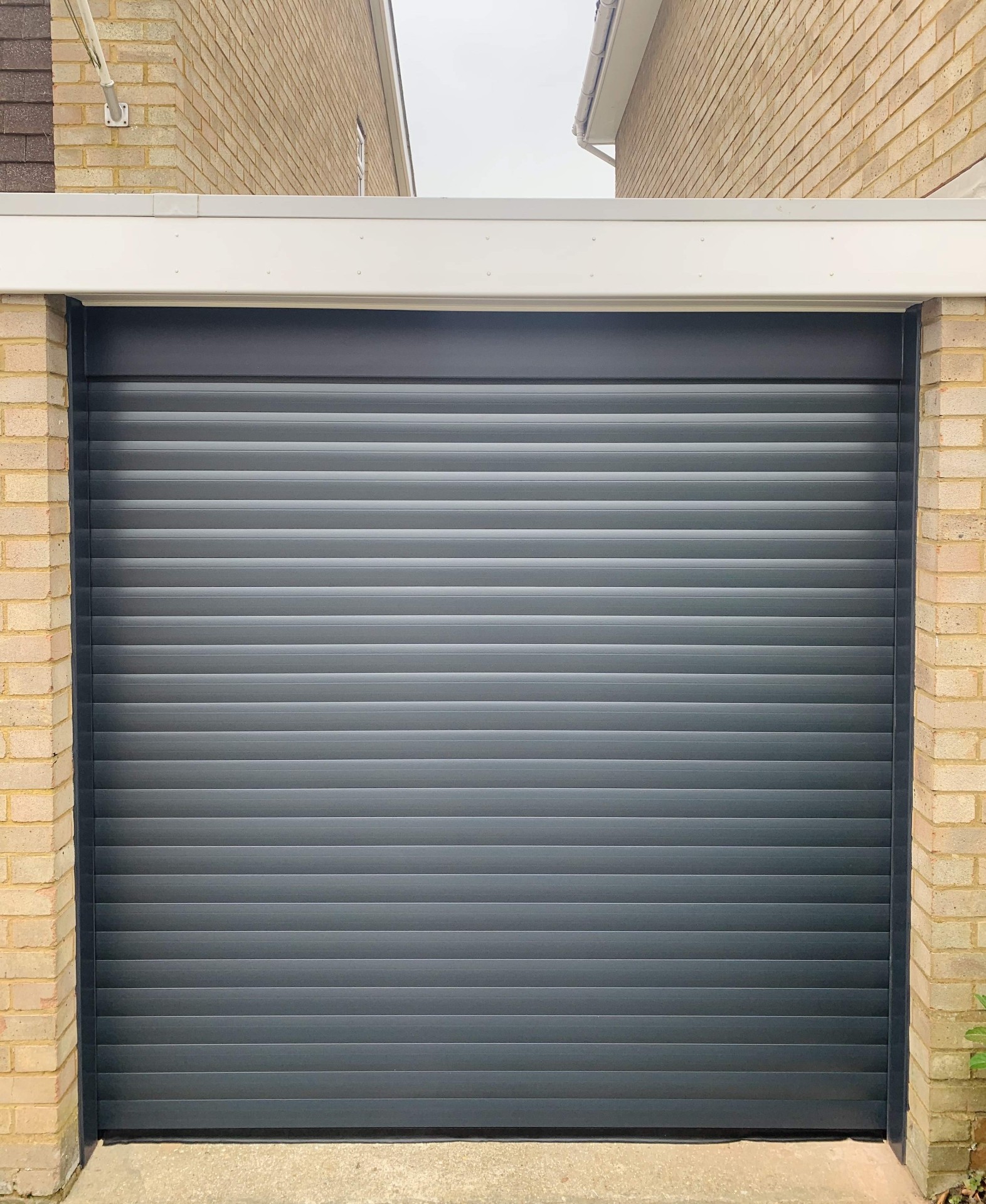 Wide double-width electric roller garage door in silver grey