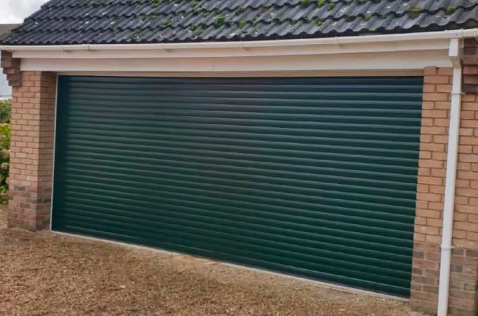 Dark green insulated electric roller garage door on a double garage with brick piers