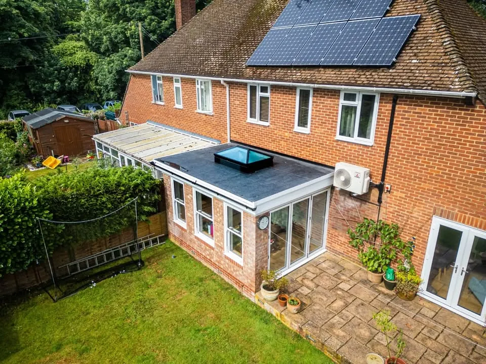 Flat conservatory roof with a glazed lantern seen from above on a brick house, Witney