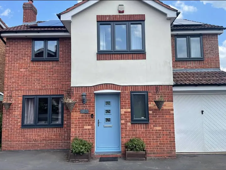 Anthracite grey casement windows with a pale blue composite front door on a brick and render house, Didcot