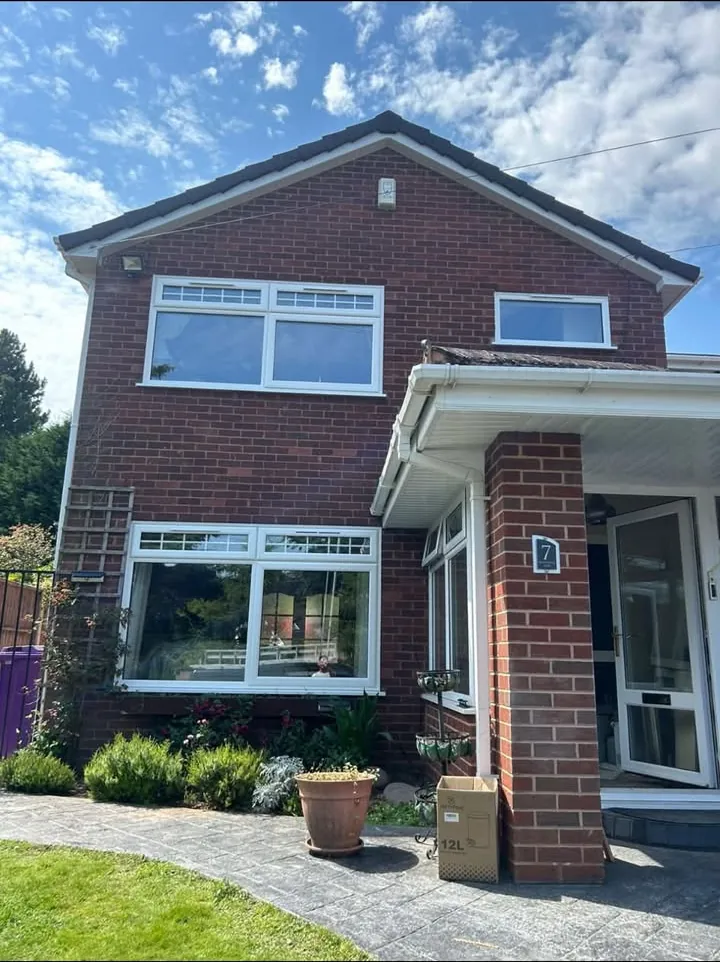 White casement windows and a wide bay window on a red brick house in bright sunshine, Grove
