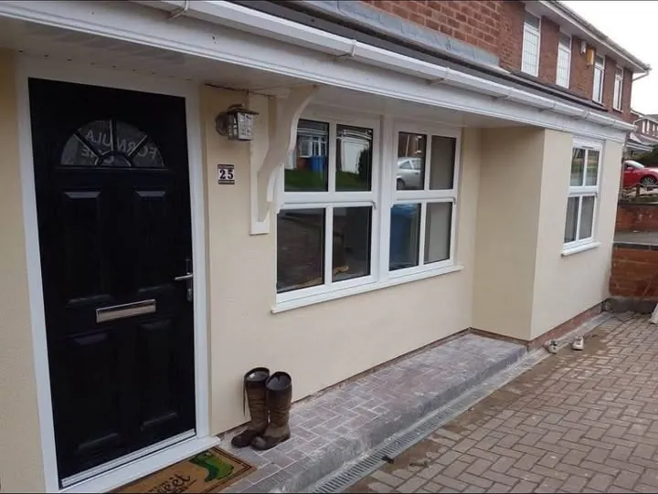 Black composite front door with an arched leaded fanlight beside white casement windows on a cream rendered house, Didcot
