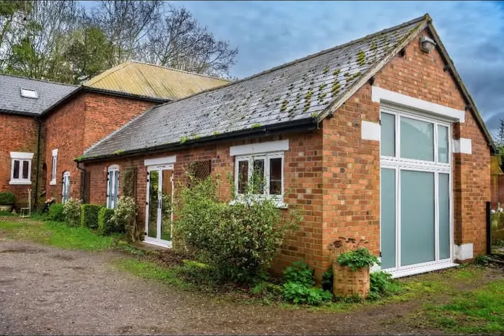 White casement windows and a full-height picture window on a red brick barn conversion