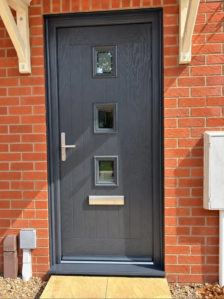 Anthracite grey cottage-style composite front door with three square glazed panels in a red brick porch, Trowbridge