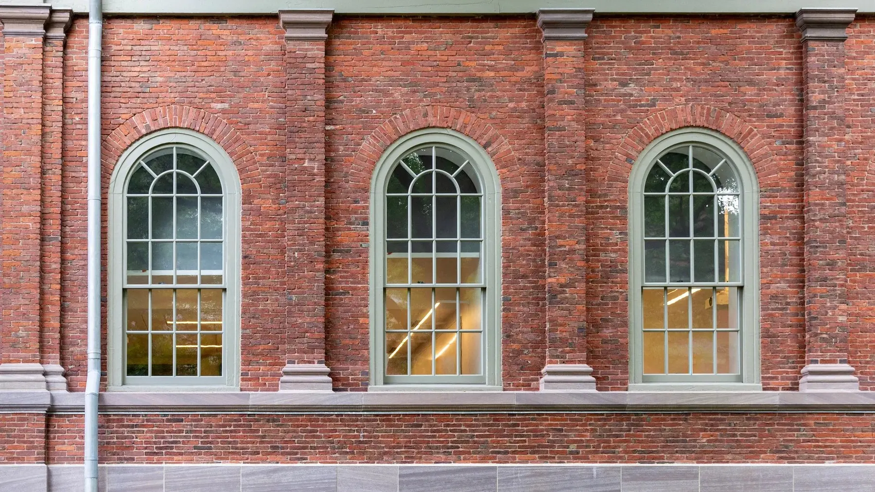 Arched sliding sash windows with glazing bars set into a red brick elevation