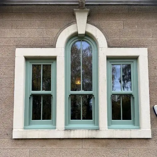 Arched centre sash flanked by two sliding sash windows in a heritage green finish