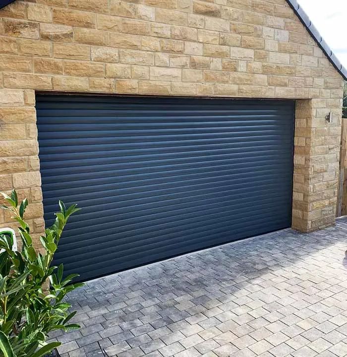 Anthracite insulated roller door set in a natural stone double garage