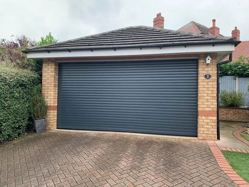 Anthracite insulated roller door on a yellow-brick double garage with a hipped roof