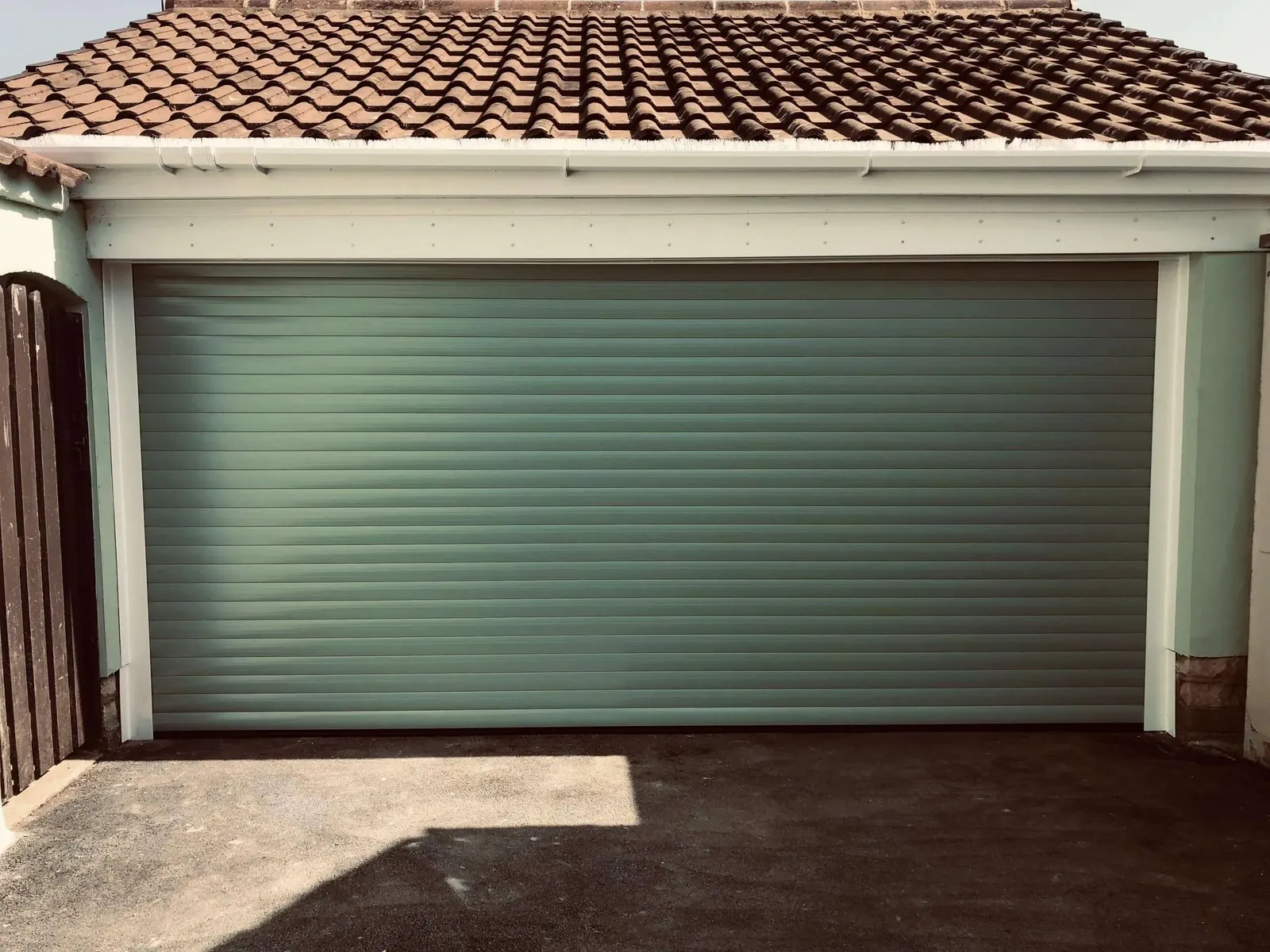 Chartwell green insulated roller door on a double garage with a tiled roof