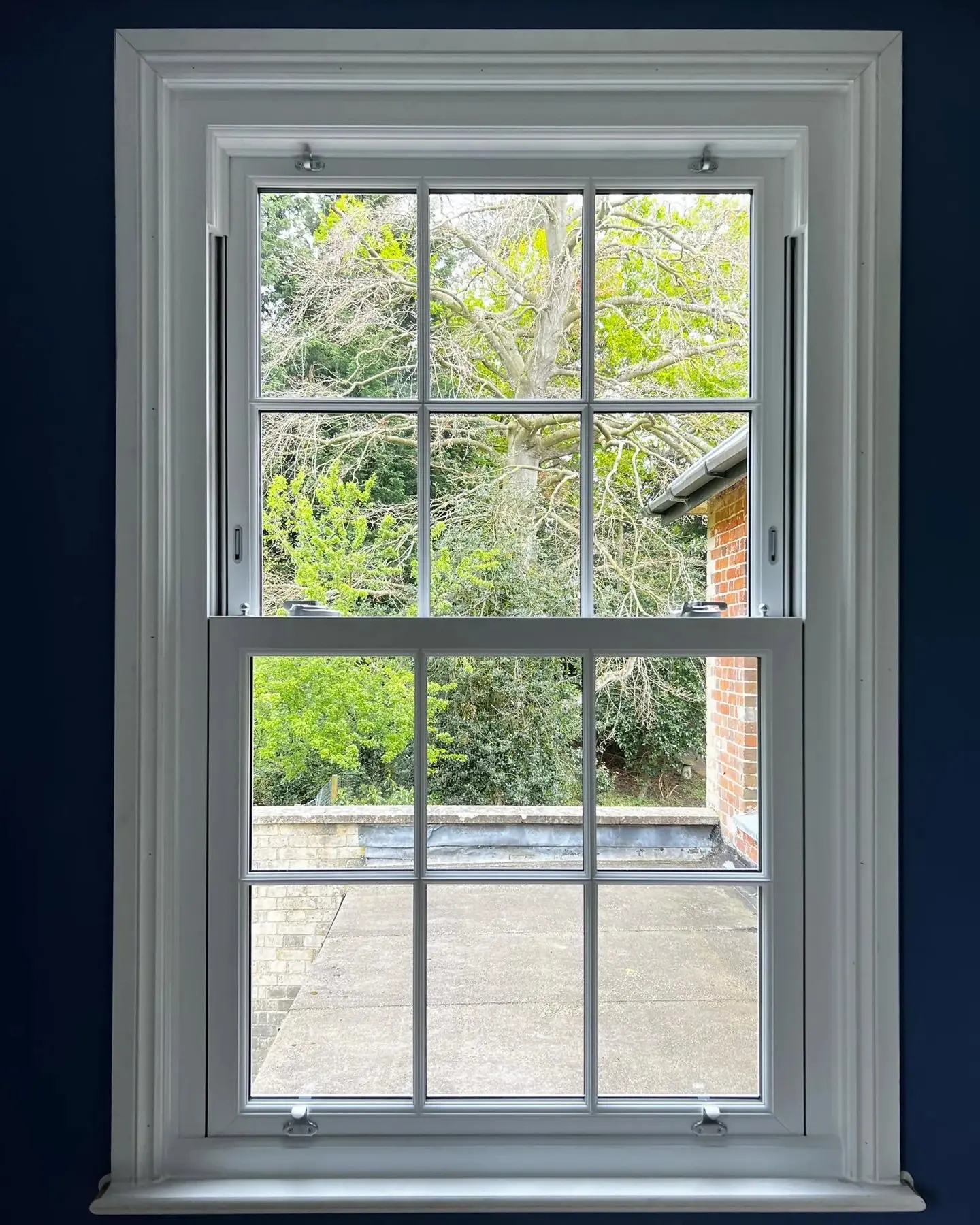 Six over six sliding sash window seen from inside, looking onto a garden
