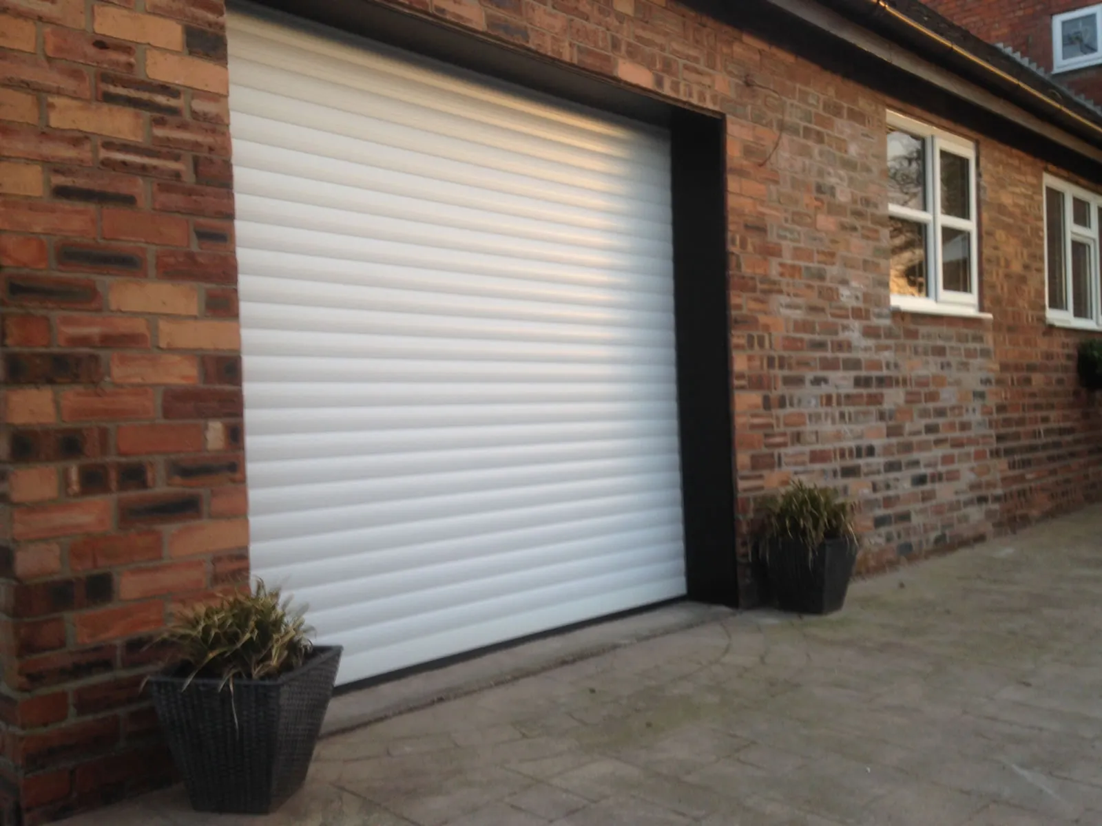 White insulated roller door set in a reclaimed-brick single garage