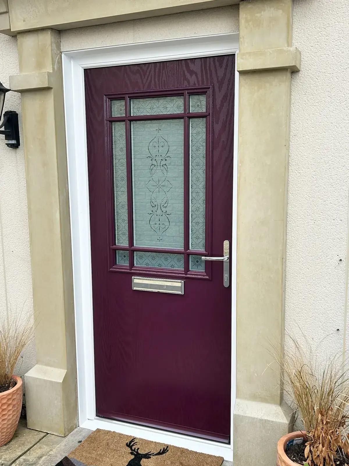 Aubergine composite front door with etched glass and Georgian-style bars, chrome handle and white frame in a stone surround, Melksham