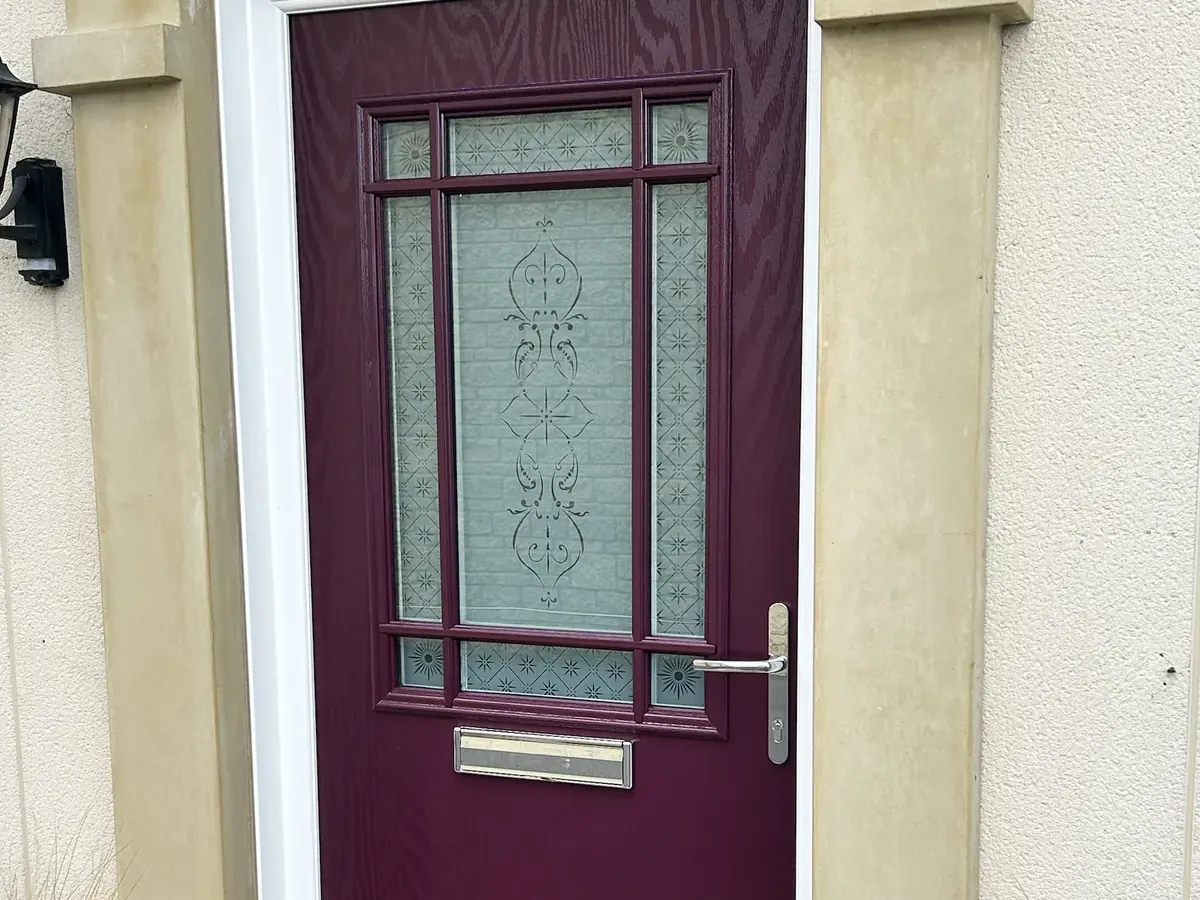 Aubergine composite front door with etched glass and Georgian-style bars, chrome handle and white frame in a stone surround, Melksham