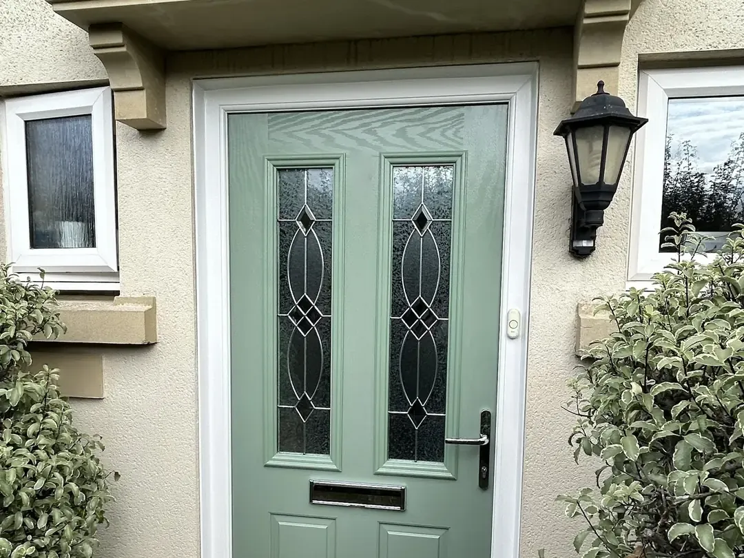 Chartwell Green composite front door with tall leaded glass panels, chrome letterplate and white frame beneath a stone canopy, Melksham