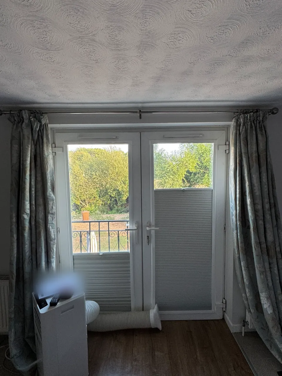 Before: white French doors onto a Juliet balcony, with a portable air conditioning hose run under the doors