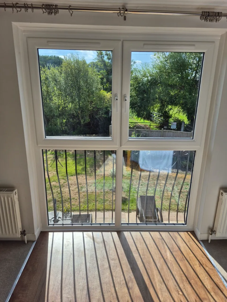 Inside view of the new white tilt and turn window, two opening sashes above full-height fixed glazing behind a Juliet balcony, Sandford-on-Thames